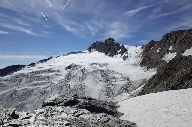 The Annakogle, at over 3300 metres, rises only slightly above its neighbours into the sky. Its dark grey, rocky peak is enclosed by the ice surfaces of the Langtaler Ferner. A breathtaking sight of white to light grey shades of the ice and snow surfaces, which form a sharp contrast to the dark grey to anthracite rock formations. Only the azure sky with a few tattered clouds adds a little colour to the scenery.